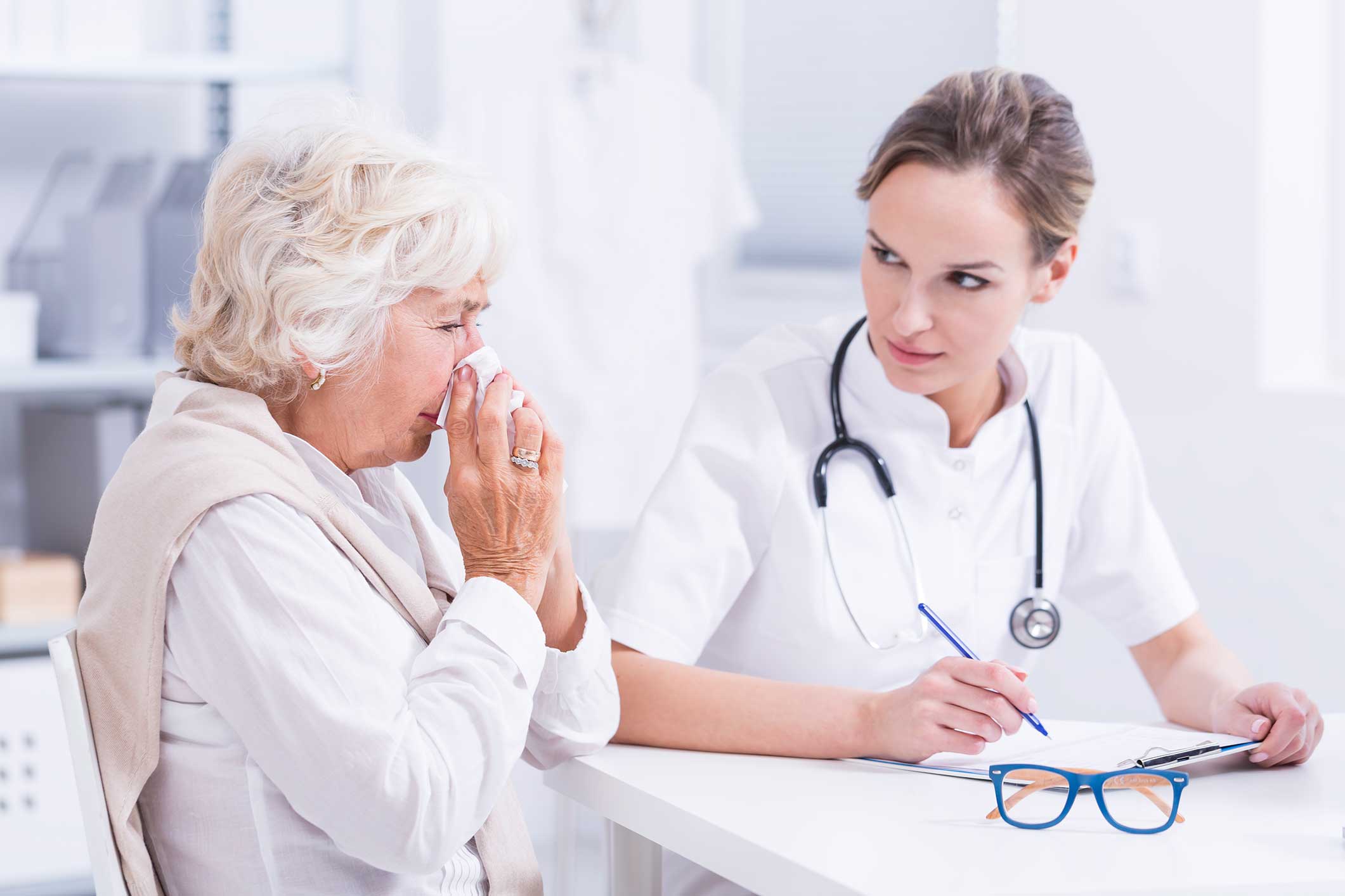 Woman blowing her nose at a doctor's office